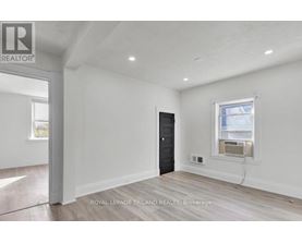 A room with a black door and a window with a view of a building outside.