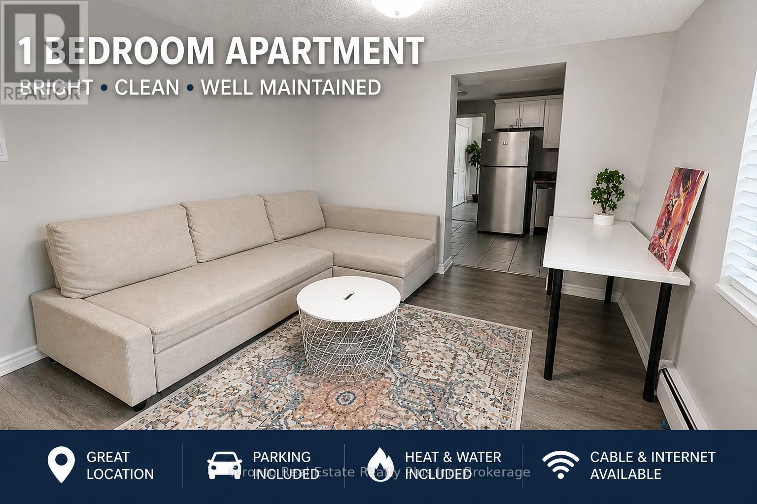 A well-lit, clean, and well-maintained 1 bedroom apartment with a couch, a small table, and a rug in the living room.