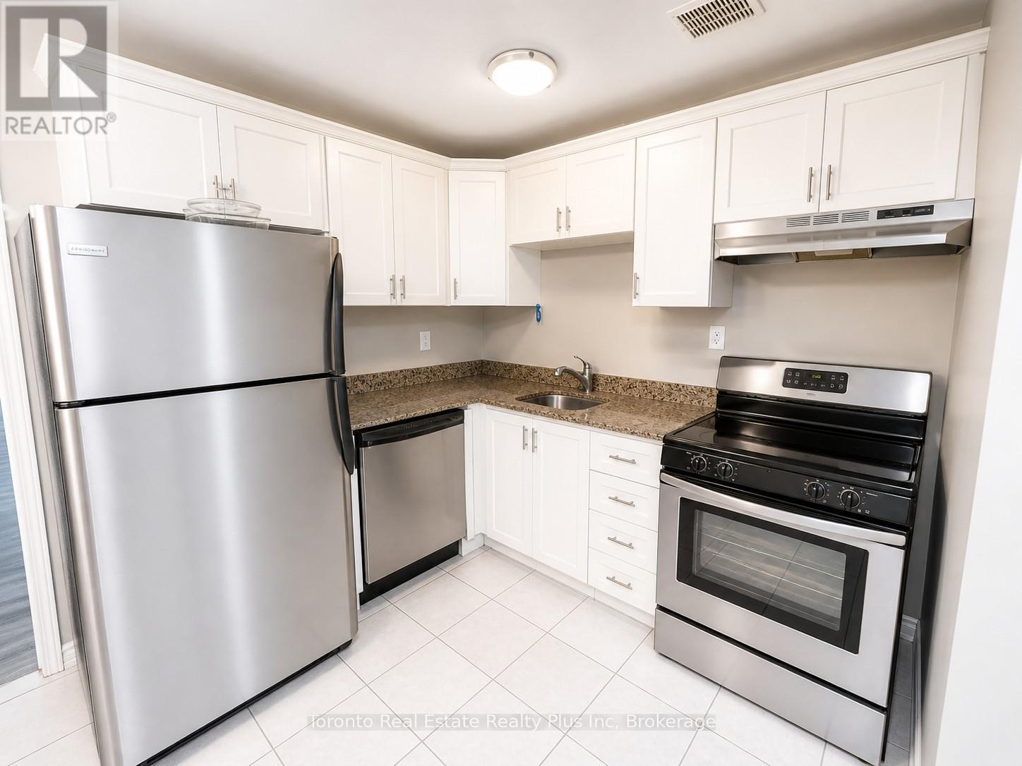 A kitchen with a refrigerator, oven, and cabinets.