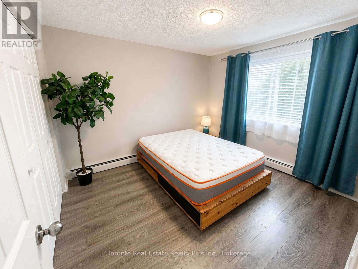 A bedroom with a bed, a plant, and a window.