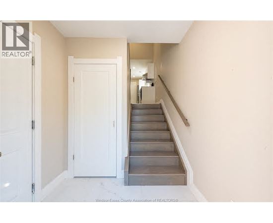 A hallway with a staircase and a door.