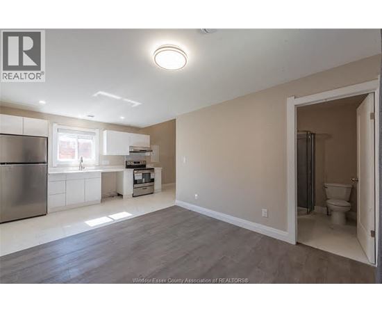 A kitchen with a refrigerator, sink, and a window.