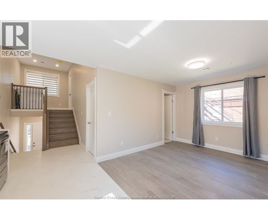 A spacious living room with a staircase leading to the upper floor.