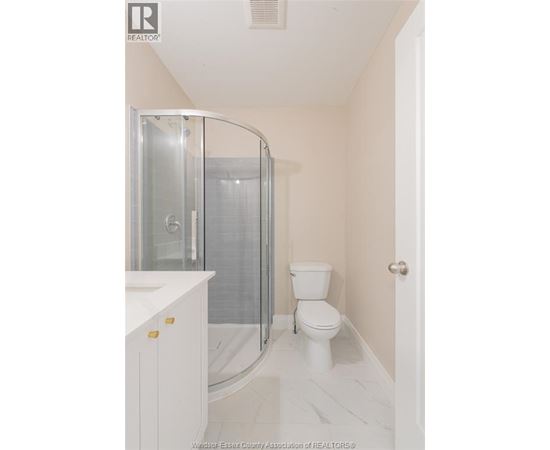 A white bathroom with a toilet, sink, and shower.