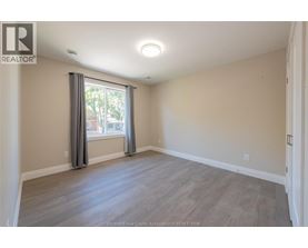 A spacious room with a large window and grey curtains.