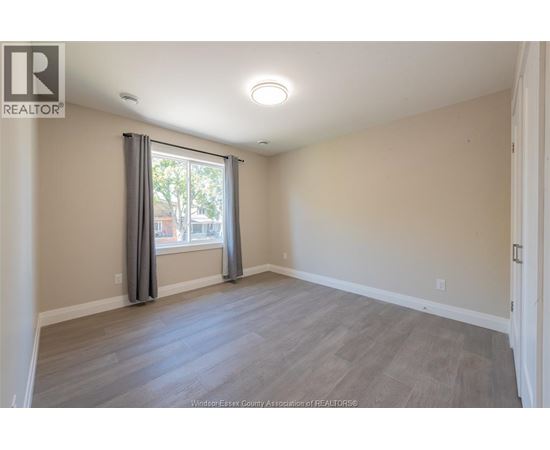 A spacious room with a large window and grey curtains.