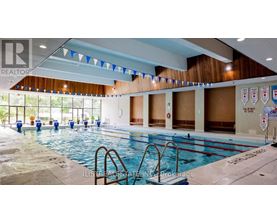 A large indoor swimming pool with a diving board and flags hanging from the ceiling.