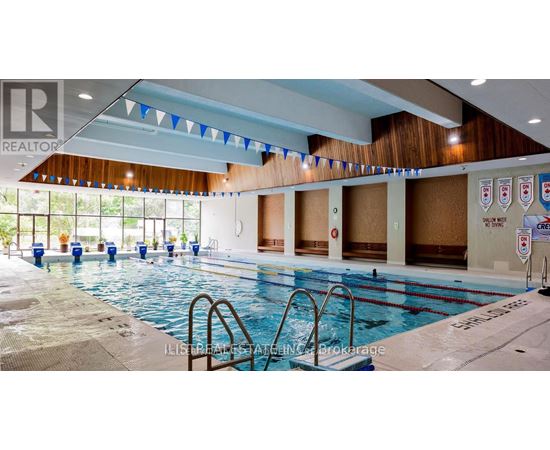 A large indoor swimming pool with a diving board and flags hanging from the ceiling.