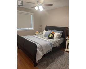 A bedroom with a bed, nightstand, and window.