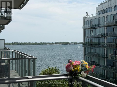 A balcony with a flower pot overlooks a body of water with boats.