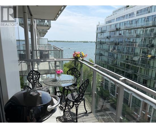 A balcony with a table and chairs overlooking a body of water.