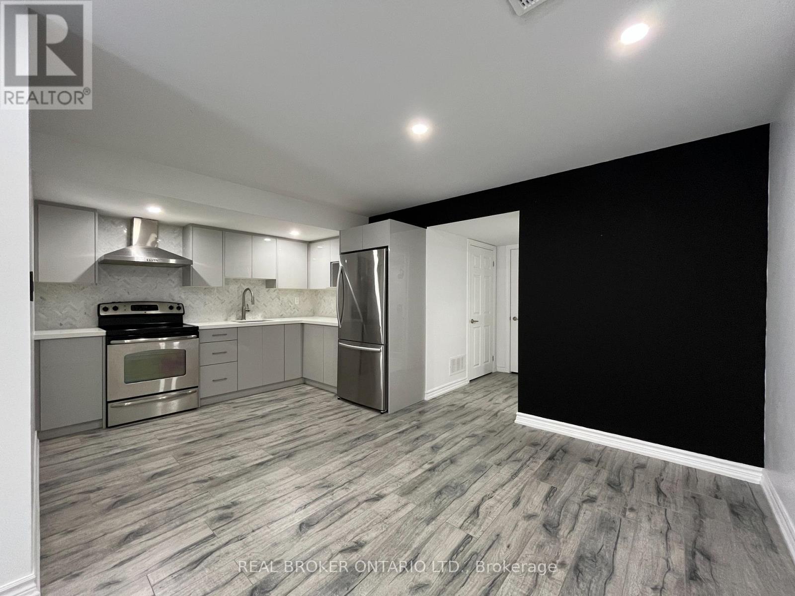 A modern kitchen with stainless steel appliances and a wooden floor.