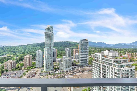 A cityscape with a mix of residential and commercial buildings, surrounded by green hills.