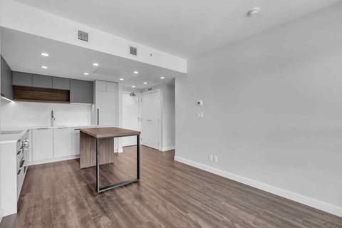 A room with a table and a kitchen area.