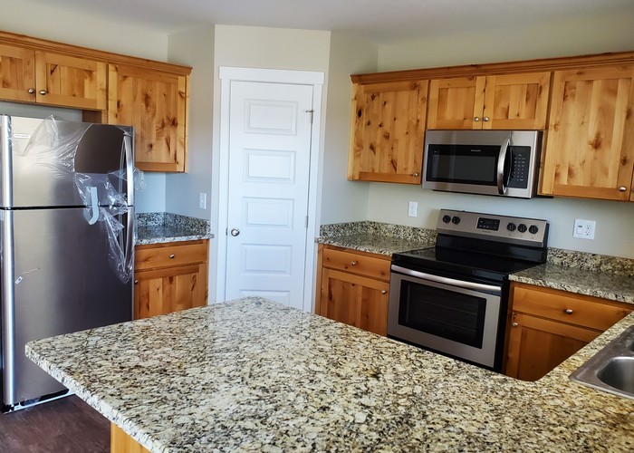 A kitchen with granite countertops and wooden cabinets.