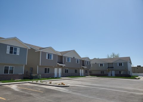 A row of houses with a parking lot in front.