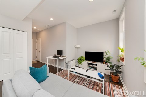 A living room with a grey couch and a television on a white stand.