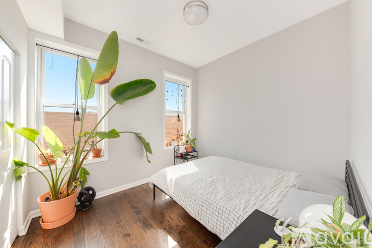 A bedroom with a bed, a potted plant, and a window.