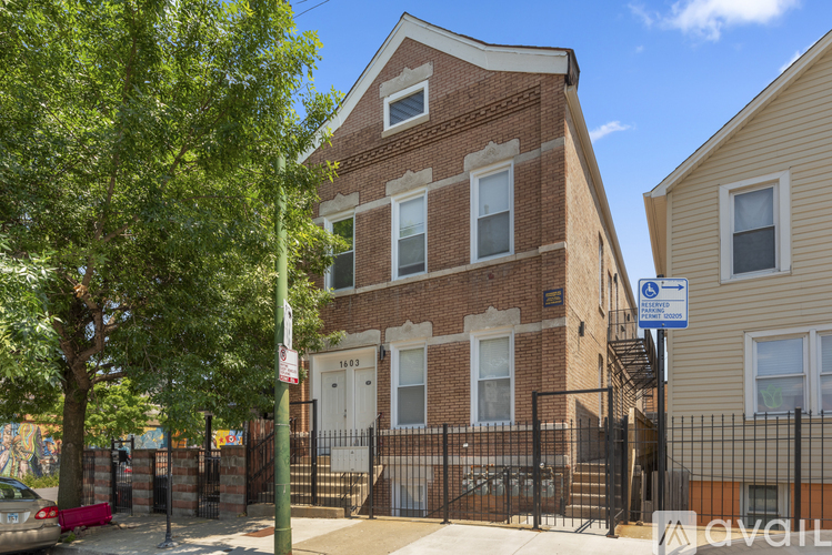 A brick building with a black iron fence in front.