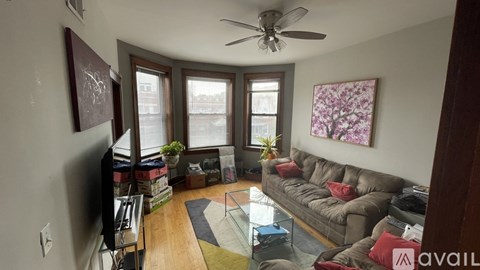 A living room with a brown couch and a ceiling fan.