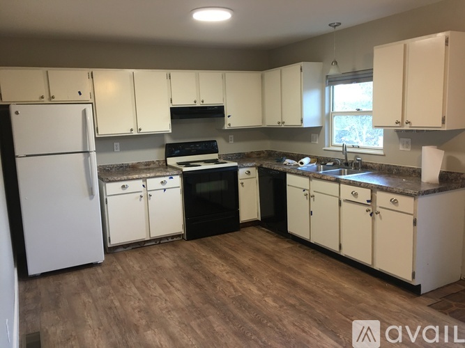 A kitchen with white cabinets and a black dishwasher.