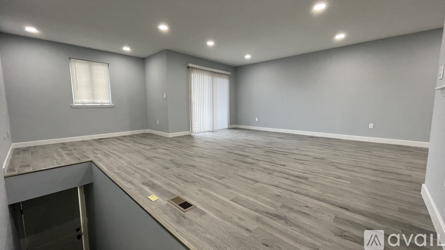 A spacious room with grey walls and wooden flooring is available for rent.