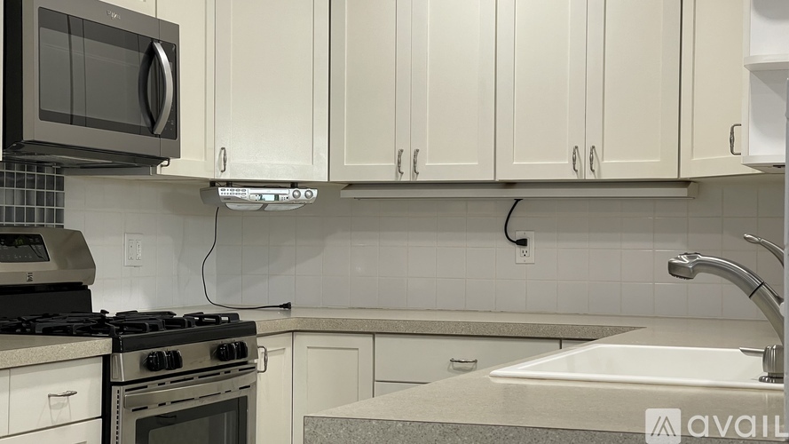 A kitchen with white cabinets and a black microwave above the stove.