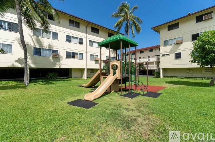 A playground with a slide and swing set in the foreground and apartment buildings in the background.