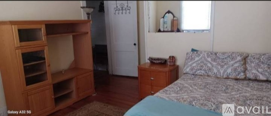 A bedroom with a bed, dresser, and a wooden entertainment center.