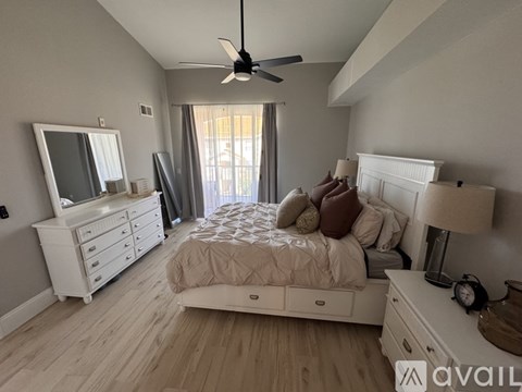 A bedroom with a large bed, a dresser, and a ceiling fan.