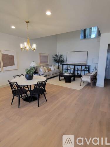 A living room with a white table and chairs, a couch, a TV, and a plant.