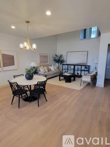 A living room with a white table and chairs, a couch, a TV, and a plant.