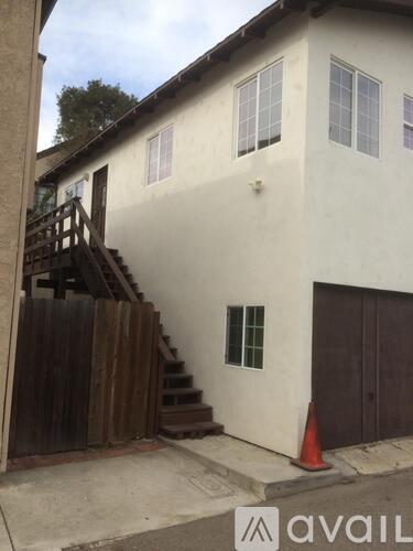 A white house with a brown door and a wooden staircase.