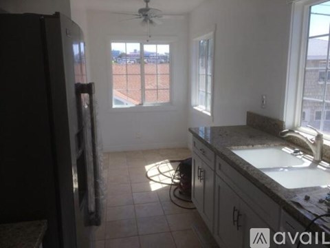 A kitchen with a refrigerator, sink, and a window overlooking a parking lot.