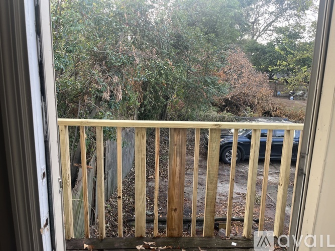 A view from a balcony looking out at a car and trees.