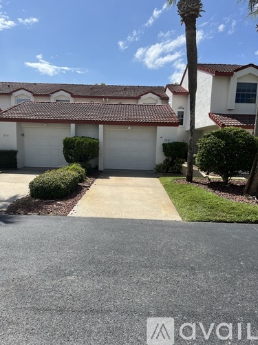 A house with a driveway and a palm tree in front.