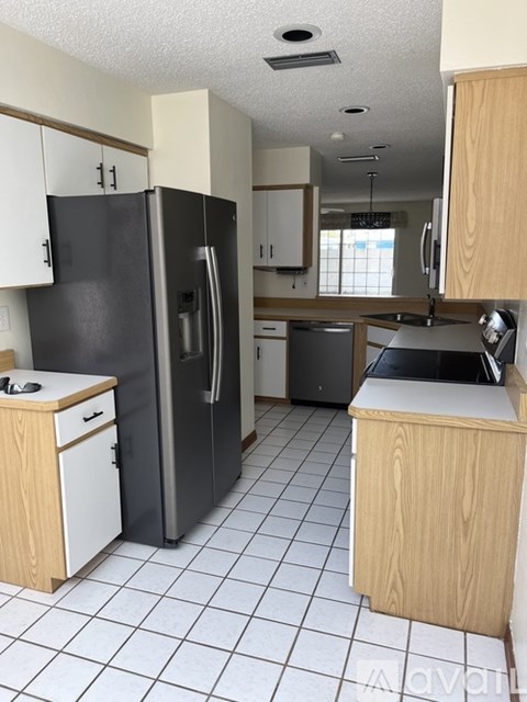 A kitchen with a black refrigerator and white cabinets.