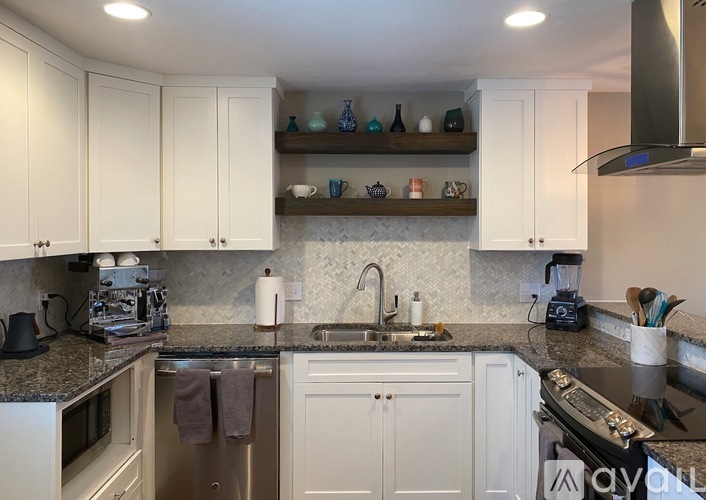 A kitchen with white cabinets and a granite countertop.