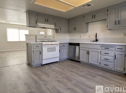 A kitchen with white cabinets and a wooden floor.