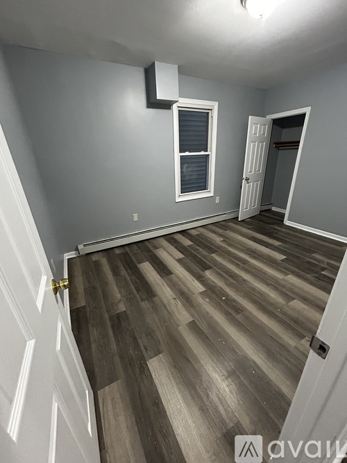 A room with wooden flooring and a white door.