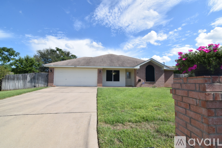 A house with a driveway and a brick pillar with flowers on it.