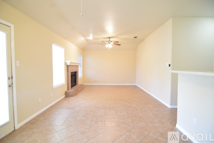 A spacious room with a fireplace and a ceiling fan.