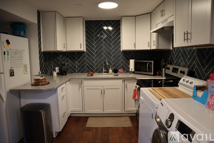 A kitchen with white cabinets and a black tile backsplash.