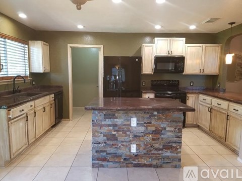 A kitchen with a stone counter top and wooden cabinets.