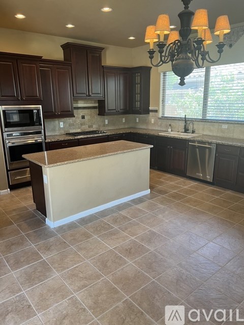 A kitchen with brown cabinets and a chandelier.