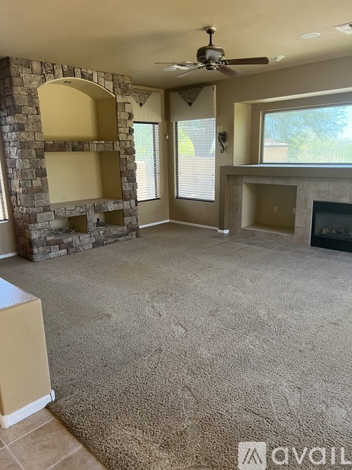 A living room with a stone fireplace and a carpeted floor.