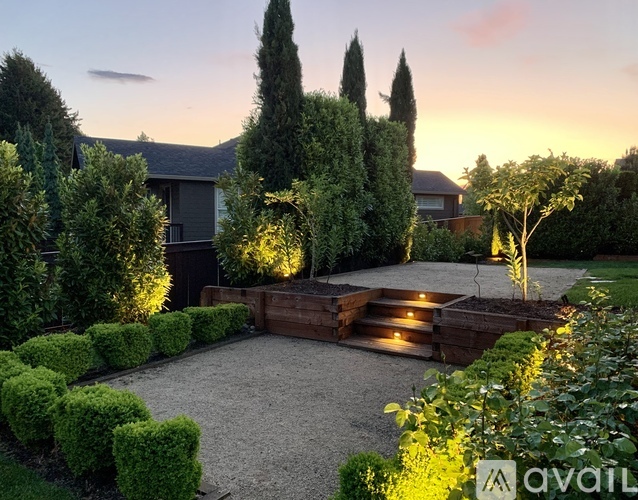 A garden with a gravel area and a wooden deck surrounded by green plants.