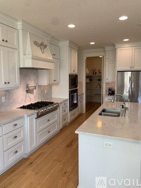 A kitchen with white cabinets and a marble countertop.