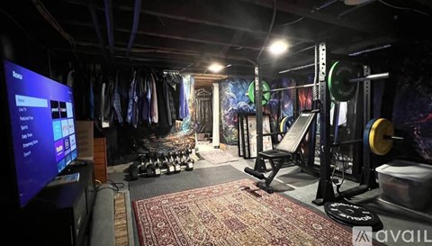 A gym with a variety of equipment including a squat rack, bench, and weights.