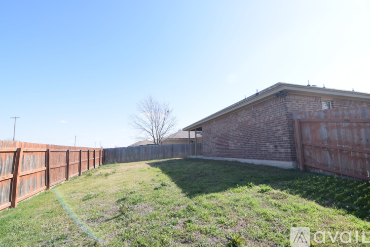 A backyard with a fence and a building in the background.